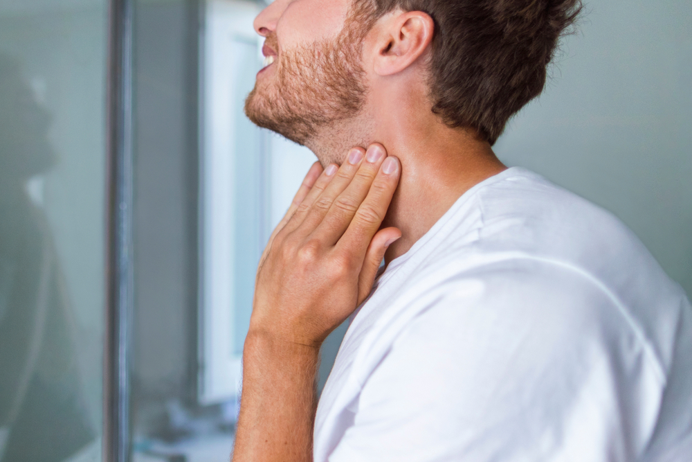 man giving Thyroid self-exam checkup.